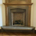 A fireplace with a brick wall and wooden mantle.